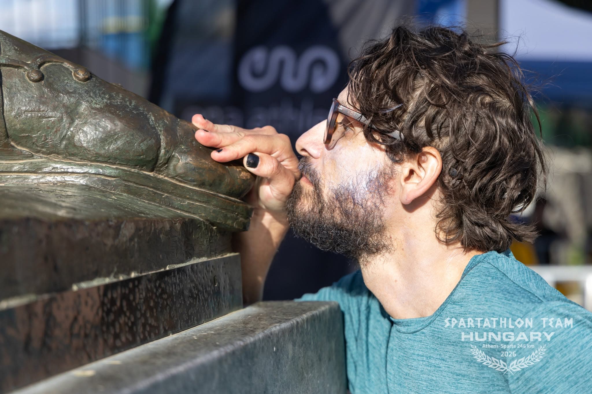 El autor, de perfil, besa el pie de bronce de la estatua de Leónidas.