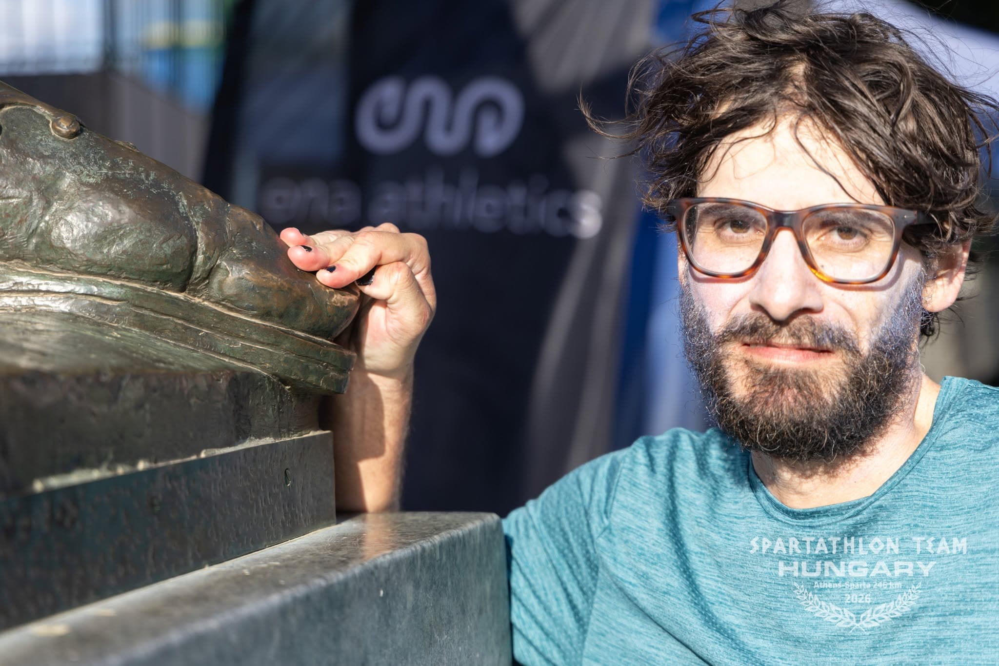 El autor mira a la cámara, cansado y tranquilo, con la mano sobre el pie de bronce de Leónidas.