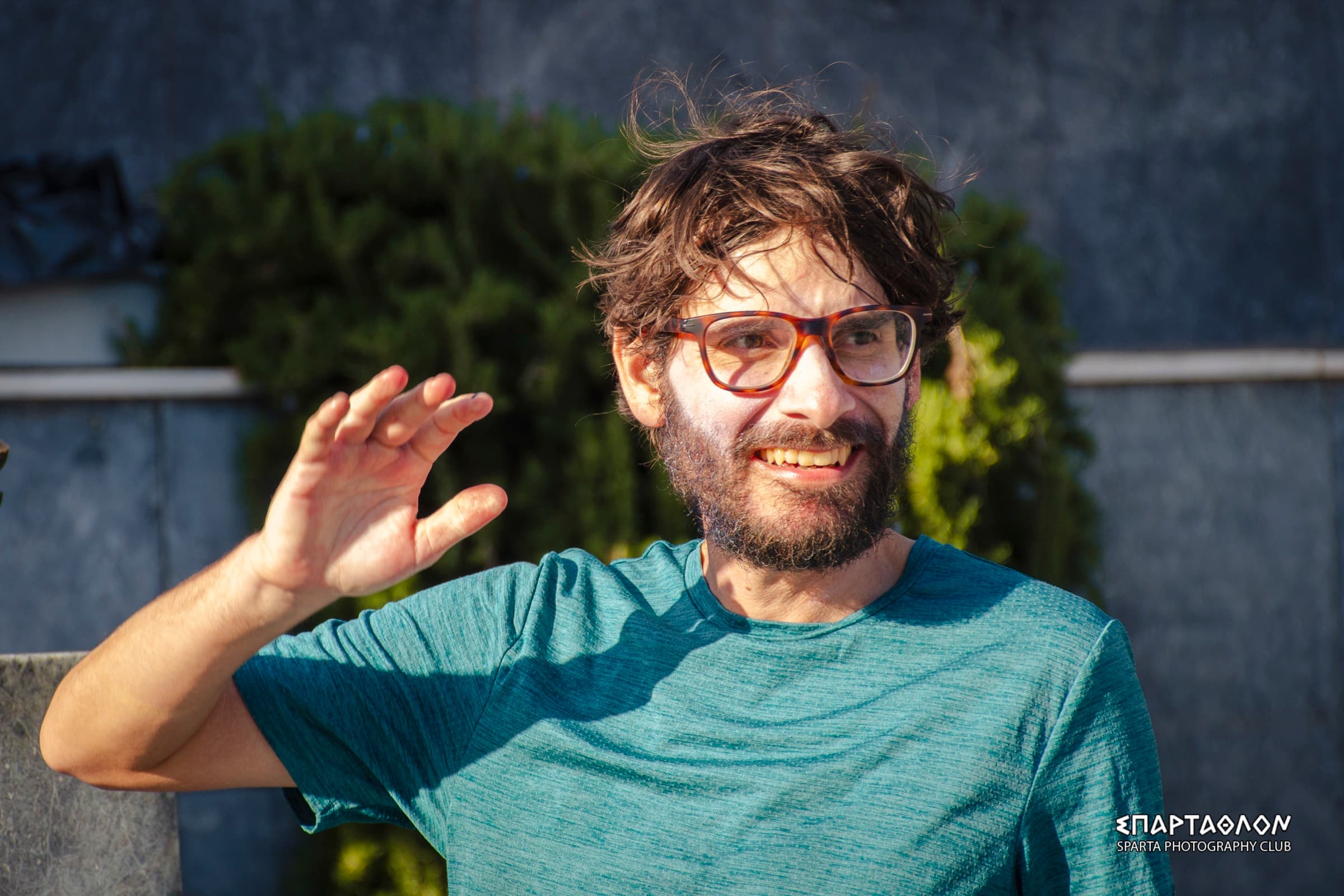El autor en la meta, despeinado y sonriendo, con una camiseta verde azulada, levanta la mano para saludar.